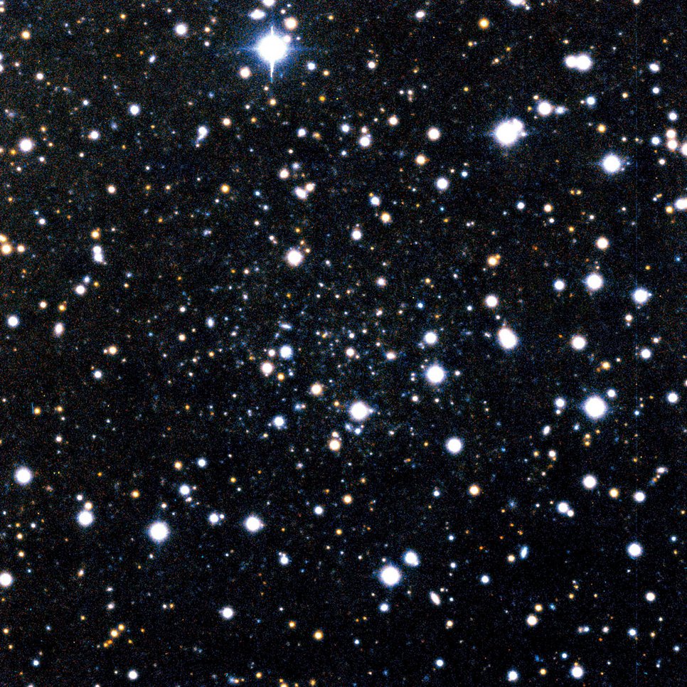 Abb. 2: Andromeda IX, die lichtschwächste jemals entdeckte Galaxie. Die meisten Sterne auf diesem Bild stehen im Vordergrund und gehören unserem eigenen Milchstraßensystem an. Andromeda IX ist als die minimale Konzentration schwacher Sterne in der Bildmitte kaum zu erkennen. Diese Galaxie ist einige 100000 Mal schwächer als die Andromeda-Galaxie oder unser Milchstraßensystem, ihr Durchmesser beträgt etwa 3000 Lichtjahre, ihre Entfernung zwei Millionen Lichtjahre.