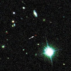 Abb. 1: Der entfernteste Quasar erscheint auf der Entdeckungsaufnahme als ein schwach leuchtendes, auffallend rotes Objekt (Pfeil)