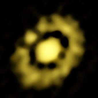 Abbildung 1: Innenbereich der Staubscheibe um den jungen Stern HL Tauri, aufgenommen mit dem VLA. Der separate Fleck bei rund 10 Uhr könnte ein Planetenembryo sein - eine Region, in der gerade ein Planet entsteht. Abbildung 1: Innenbereich der Staubscheibe um den jungen Stern HL Tauri, aufgenommen mit dem VLA. Der separate Fleck bei rund 10 Uhr könnte ein Planetenembryo sein - eine Region, in der gerade ein Planet entsteht.