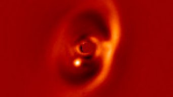 Nah-Infrarot-Aufnahme der PDS70-Scheibe aufgenommen mit dem SPHERE-Instrument. Der junge Exoplanet PDS 70 b ist deutlich als helles Signal am inneren Rand der Lücke (dunkler Bereich) zu erkennen. Die vom Zentralstern ausgehende Emission wurde ausgeblendet. Der Balken rechts unten zeigt den linearen Maßstab des Bildes in einer Entfernung von 370 Lichtjahren an. Nah-Infrarot-Aufnahme der PDS70-Scheibe aufgenommen mit dem SPHERE-Instrument. Der junge Exoplanet PDS 70 b ist deutlich als helles Signal am inneren Rand der Lücke (dunkler Bereich) zu erkennen. Die vom Zentralstern ausgehende Emission wurde ausgeblendet. Der Balken rechts unten zeigt den linearen Maßstab des Bildes in einer Entfernung von 370 Lichtjahren an.