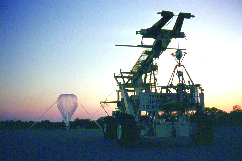 THISBE vor dem Start vom Flugplatz der National Center for Atmospheric Research in Palestine, Texas. Im Hintergrund wird ein 50 000 m³ Plastik-Ballon zu 1% seines Volumens mit Helium gefüllt. Beim Aufstieg dehnt sich das Gas aus und füllt schließlich die gesamte Ballonhülle. Da der Ballon unten offen ist, sind dort Innen- und Außendruck gleich. Deshalb reicht die dünne Plastikhülle (25 Mikrometer) aus, um das Füllgas gefangen zu halten. In 33 km Höhe sind 99% der Atmosphäre überwunden, beim Flug auf 41 km Höhe sogar 99,6%. © Dietrich Lemke