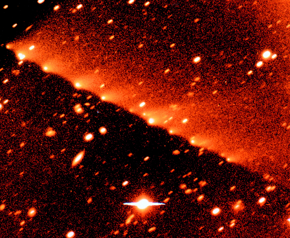 Vor dem Einschlag: Der Komet Shoemaker-Levy 9 aufgenommen mit einer CCD-Kamera am 3.5-m-Teleskop auf dem Calar Alto am 5. Mai 1994. Bei einem engen Vorbeiflug des Kometen am Jupiter im Jahre 1992 haben Gezeitenkräfte den ursprünglichen ~1km großen Kern in ~20 größere Trümmerstücke zerlegt. Hier sieht man die meisten, auseinander gezogen über eine Strecke von 800000 km. Jedes Bruchstück zeigt einen eigenen, von der Sonne wegweisenden Schweif. © Kurt Birkle
