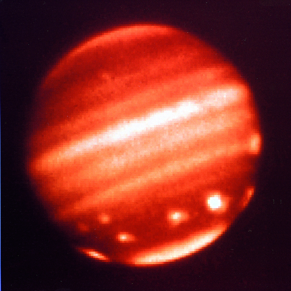 Jupiter im Infrarotlicht aufgenommen mit der MAGIC-Kamera am 3.5-m-Teleskop auf dem Calar Alto am 19.Juli 1994. Inzwischen waren die Hälfte der größeren Trümmerstücke auf dem Jupiter eingeschlagen. Die dabei in der Atmosphäre erzeugten Wolken hatten sich wie eine Perlenkette im Süden um den Planeten gelegt. Ein einmaliger Anblick, der daran erinnert, dass Planeten auch heute noch von großen Trümmern getroffen werden könnem. Auf der Erde hätte ein solcher Einschlag eine Katastrophe ausgelöst. © Tom Herbst
