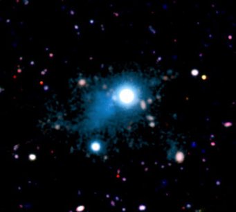 Abbildung 1: Der beobachtete Ausschnitt des kosmischen Netzwerks (türkisfarben) mit einer Ausdehung von rund 2 Millionen Lichtjahren, der in der direkten Umgebung des Quasars UM 287 (Bildmitte) beobachtet wurde. Das Gas leuchtet dank desselben Effekts, dem auch Leuchtstoffröhren ihr Licht verdanken. Dies ist das erste Bild eines Teils des kosmischen Netzwerks aus Gasfilamenten, das eine Schlüsselrolle für die Sternentstehung in Galaxien spielen dürfte. Abbildung 1: Der beobachtete Ausschnitt des kosmischen Netzwerks (türkisfarben) mit einer Ausdehung von rund 2 Millionen Lichtjahren, der in der direkten Umgebung des Quasars UM 287 (Bildmitte) beobachtet wurde. Das Gas leuchtet dank desselben Effekts, dem auch Leuchtstoffröhren ihr Licht verdanken. Dies ist das erste Bild eines Teils des kosmischen Netzwerks aus Gasfilamenten, das eine Schlüsselrolle für die Sternentstehung in Galaxien spielen dürfte.