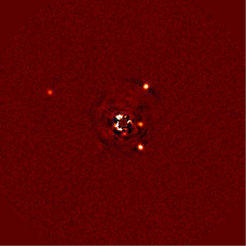 Abb. 1: Direkte Abbildung des Planetensystems um HR8799. Links der Planet HR8799b, auf der rechten Seite, von oben nach unten, die Planeten c, e und d. Der Stern ist mithilfe einer Maske weitgehend ausgeblendet; Reste seines Lichts führen zu den Spuren in der Bildmitte.