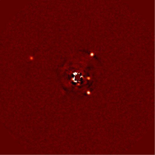 Abb. 1: Direkte Abbildung des Planetensystems um HR8799. Links der Planet HR8799b, auf der rechten Seite, von oben nach unten, die Planeten c, e und d. Der Stern ist mithilfe einer Maske weitgehend ausgeblendet; Reste seines Lichts führen zu den Spuren in der Bildmitte.