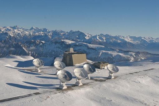Abbildung 5: Das IRAM-Interferometer auf dem Plateau de Bure in den französischen Alpen. Im Hintergrund die südöstlichen Ausläufer der französischen Alpen. Mit diesem Verbundteleskop wurden die ersten der Spektrallinien von HDF850.1 gefunden, mit deren Hilfe sich die Entfernung der Submillimeter-Galaxie bestimmen ließ. Abbildung 5: Das IRAM-Interferometer auf dem Plateau de Bure in den französischen Alpen. Im Hintergrund die südöstlichen Ausläufer der französischen Alpen. Mit diesem Verbundteleskop wurden die ersten der Spektrallinien von HDF850.1 gefunden, mit deren Hilfe sich die Entfernung der Submillimeter-Galaxie bestimmen ließ.