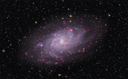 Abbildung 1: Bild des Dreiecksnebels M 33. Bei dieser Galaxie sehen die Astronomen direkt von oben auf die Scheibe mit ihren Spiralarmen. Die rosa Regionen enthalten neu geborene Sterne.