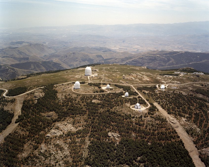 Abb. 1: Das Calar-Alto-Observatorium. Blick von Norden auf die Teleskopkuppeln. Von links nach rechts: das 2.2-meter-Teleskop, das spanische 1.5-Meter-Teleskop (im Vordergrund), das 1.2-Meter-Teleskop, der Schmidt-Spiegel und die 43 Meter hohe Kuppel des 3.5-Meter-Teleskops. Im Hintergrund die Küste bei Almeria. Abb. 1: Das Calar-Alto-Observatorium. Blick von Norden auf die Teleskopkuppeln. Von links nach rechts: das 2.2-meter-Teleskop, das spanische 1.5-Meter-Teleskop (im Vordergrund), das 1.2-Meter-Teleskop, der Schmidt-Spiegel und die 43 Meter hohe Kuppel des 3.5-Meter-Teleskops. Im Hintergrund die Küste bei Almeria.
