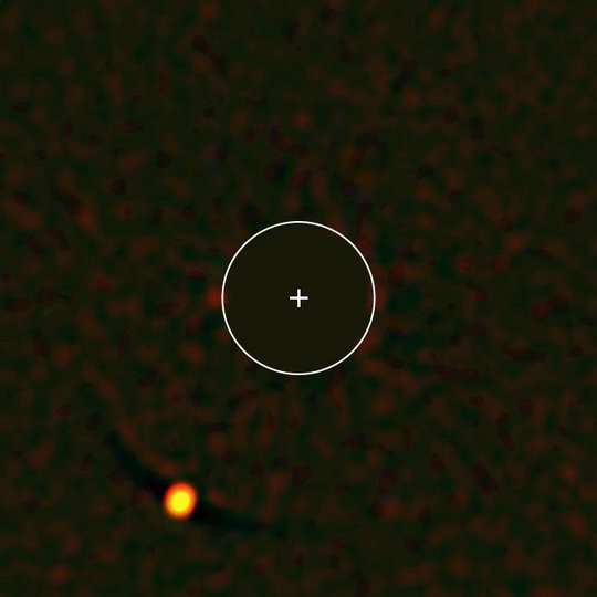 Abbildung des Planeten HIP 65426b (links unten), aufgenommen mit dem SPHERE-Instrument. SPHERE blendet dabei das Licht des Zentralsterns in der Bildmitte aus (blockierter Bereich = eingezeichneter Kreis), so dass das deutlich schwächere Licht des Planeten sichtbar wird. Das vom Planeten empfangene Licht lässt Rückschlüsse auf dessen Eigenschaften zu – in diesem Falle beispielsweise auf das Vorhandensein von Wasserdampf und rötlichen Wolken.