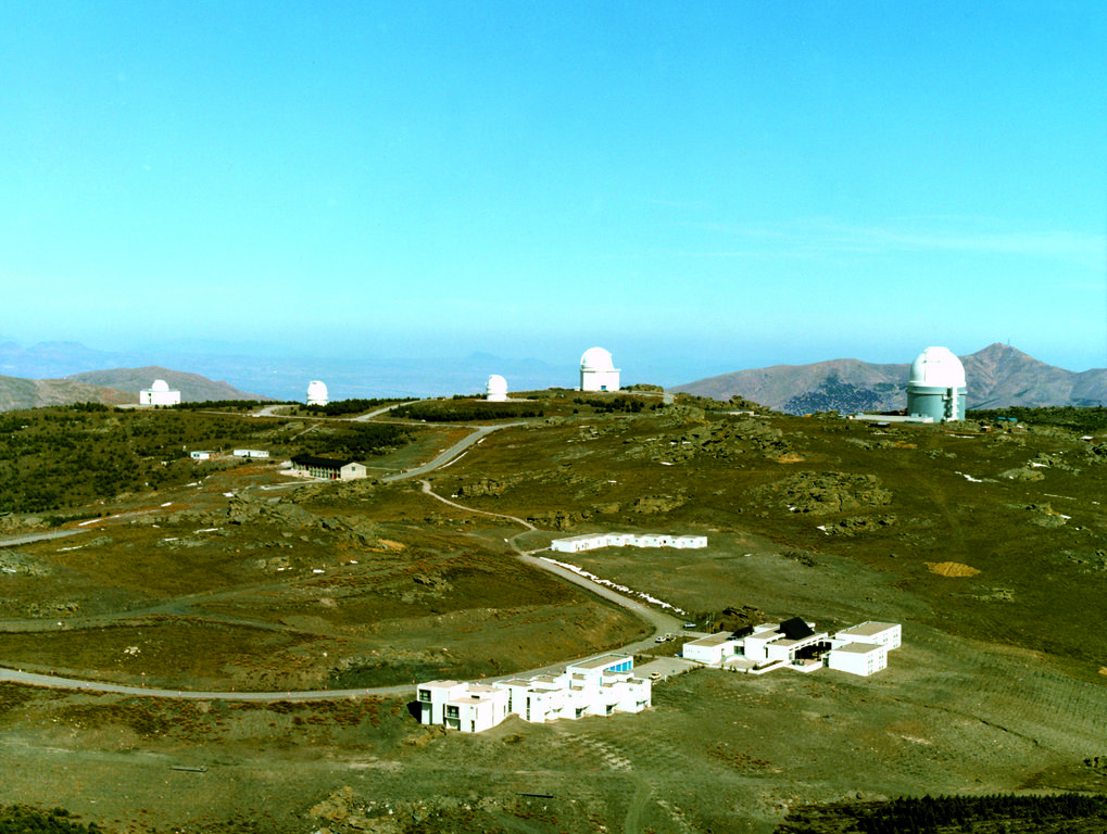 Die Calar-Alto-Sternwarte in 2160 m Höhe. Von rechts: 3.5-m-, 2.2-m-, 1.23-m-, Schmidt-, spanisches 1.5-m-Teleskop. Links der Bildmitte das Auswerte- und Werkstattgebäude, rechts die Astronomenwohnungen. Im Vordergrund Cafeteria und Mitarbeiterwohnungen. Inzwischen ist das Gelände etwas grüner, nachdem sich der örtliche Direktor Kurt Birkle mit der spanischen Naturschutzbehörde Icona auf die Bepflanzung des Gipfelbereiches mit dort natürlich vorkommenden Pflanzen und die Nichtweiterbeweidung durch Schafe geeinigt hatte. © Atair-Foto, Madrid