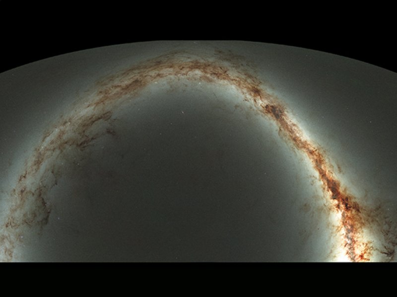 Diese verkleinerte Ansicht des gesamten Himmels, der vom Standort des Pan-STARRS Observatoriums auf Hawai'i sichtbar ist, ist das Ergebnis einer halben Million Aufnahmen mit jeweils etwa 45 Sekunden Belichtungszeit über einen Zeitraum von 4 Jahren. Die Form ergibt sich aus der Darstellung der Himmelskugel als zweidimensionale Karte, ähnlich einer Weltkarte, wobei das südliche Viertel weggelassen wurde. Die Scheibe der Milchstraße ist als gelblicher Bogen zu sehen, der Staub erscheint als rötlichbraune Filamente. Der Hintergrund besteht aus Milliarden von schwachen Sternen und Galaxien. Würde das Bild in voller Auflösung gedruckt, wäre es über 2 Kilometer lang; gleichzeitig müssten Sie sehr genau hinsehen um alle Details zu erkennen.