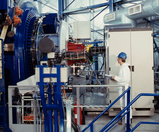 Portrait of an instrument. NAOS-CONICA installed at the 8.2 m telescope Yepun, which is part of the VLT. The dark blue ring on the left is the telescope adapter; the adaptive optics system NAOS is the adjacent light-blue part, and the camera CONICA is contained in the red cryostat. The white cabinet contains electronics used to control the instrument.