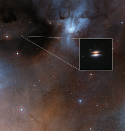 The Rho Ophiuchus star formation region at a distance of about 400 light-years from Earth. The inset shows an infrared image of the Flying Saucer protoplanetary disk, taken with the Hubble Space Telescope. Recent observations of this disk have revealed dust in that disk to have an unexpectedly low temperature.