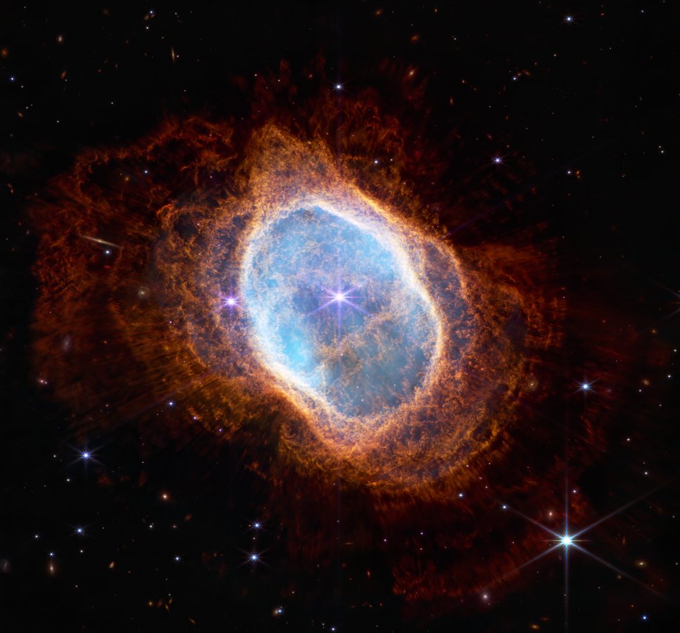 A luminous turquoise oval structure surrounded by an orange, flaky envelope against a black background. In the centre a bright luminous dot.