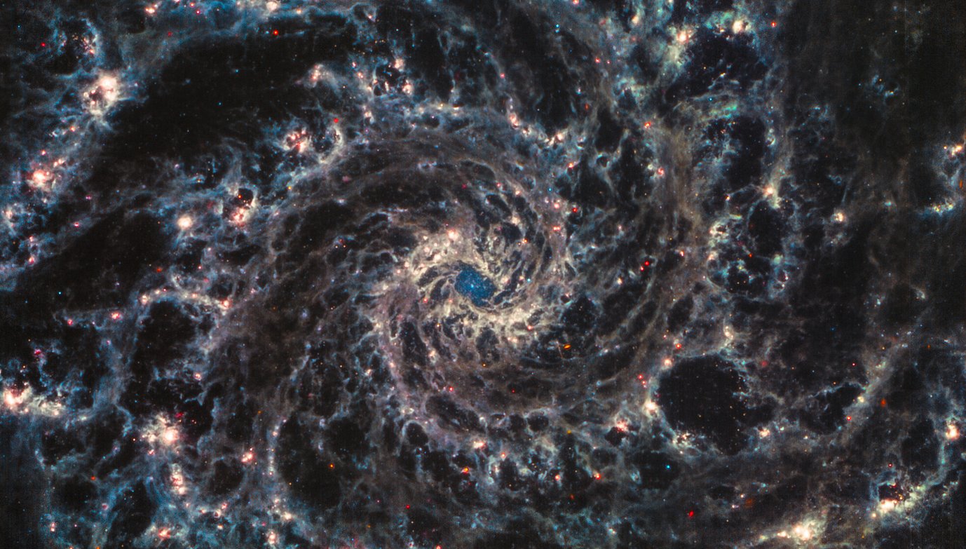 New JWST imagery is giving scientists their first look at high resolution into the fine structure of nearby galaxies and how that’s impacted by the formation of young stars. This three-colour composite image shows NGC 628 (M 74), a grand-design spiral galaxy at a distance of 32 million light-years. The picture combines MIRI images obtained at wavelengths of 21.0 (red), 11.3 (orange), 7.7 (cyan), and 10.0 (greyscale) microns. While the galactic centre is surrounded by intricated lanes of glowing dust, there is an unobscured Nuclear Star Cluster (NSC) visible in its core. These data also provide strong evidence for newly formed stars in the “spurs” of gas and dust emanating from spiral arms.