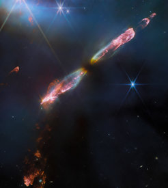 The image of HH 211 shows a series of bow shocks, radiation triggered by gas collisions, in the southeast (lower left) and northwest (upper right), and the embedded narrow bipolar jet that drives them, in unprecedented detail. This series of shock events indicates an episodic release of gas directly related to the growth of the protostar by infalling dust and gas.