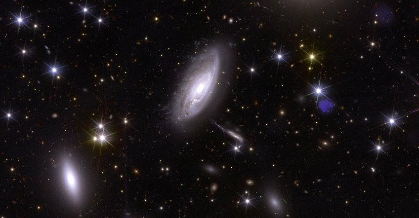 Euclid's strength lies in its diversity: this small section of Euclid's large image plane shows a detail of the Perseus galaxy cluster. Clearly recognizable are both the various types and shapes of galaxies as part of the cluster in the foreground at a distance of 240 million light years and a series of faint, diffuse spots in the background - galaxies whose light has been travelling for billions of years before Euclid imaged it. A tidy-looking picture with elliptical, bluish glowing spots of various sizes in the foreground, some with recognisable structures reminiscent of a vortex, against a black background with scattered sharp, bluish dots and yellowish diffuse spots.