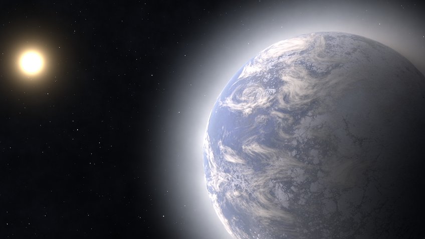 Artistic representation of an exoplanet whose water ice on the surface is increasingly vaporizing and forming an atmosphere during its approach to the central star of the planetary system. This process increases the measured planetary radius compared to the value the planet would have at its place of origin. On the right, in the foreground, is a primarily blue planet with white areas and surrounded by a hazy shell. In the background on the left, we see a brightly shining disk whose diameter is about 1/6 the planet’s size. Both objects are located in front of a black background with occasional bright dots.