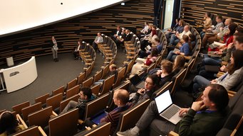 Dilara Betz (DeSK e. V.) welcomes participants to the auditorium of the Haus der Astronomie for a series of keynote speeches in which the four companies introduce themselves. Dilara Betz (DeSK e. V.) welcomes participants to the auditorium of the Haus der Astronomie for a series of keynote speeches in which the four companies introduce themselves.