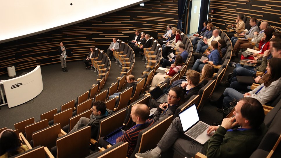 Dilara Betz (DeSK e. V.) begrüßt die Anwesenden im Auditorium des Hauses der Astronomie zu einer Reihe von Impulsvorträgen, in denen sich die vier Unternehmen vorstellen.