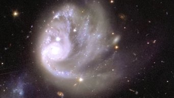 This image shows an area of the mosaic released by ESA’s Euclid space telescope on 15 October 2024. The area is zoomed in 600 times compared to the large mosaic. In this image, a single spiral galaxy (ESO 364-G036) is visible in great detail, 420 million light-years from us. This image shows 0.0003% of the initial image of 208 gigapixels, that is 1/330 000 of the area of the main Euclid mosaic. The centre of the image shows a large white swirl of light, framed by a sea of blackness and a few individual dots and smears of colour in the background. Off-centre to the left of this spiral sits a gleaming circle, the brightest spot of the image. Starting at this white ball of light, sparkling arches trace the shape of a tornado rotating clockwise, spewing glitter into empty space across the image.