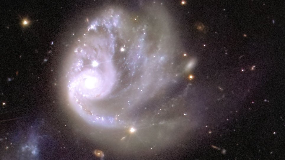 In der Mitte des Bildes ist eine große weiße Lichtspirale zu sehen, die von einem Meer aus Schwärze und einigen einzelnen Farbpunkten und -flecken im Hintergrund eingerahmt wird. Links neben dieser Spirale befindet sich ein leuchtender Kreis, der hellste Punkt des Bildes. Von dieser weißen Lichtkugel ausgehend, zeichnen funkelnde Bögen die Form eines Tornados nach, der sich im Uhrzeigersinn dreht und Glitzer in den leeren Raum quer über das Bild verteilt.