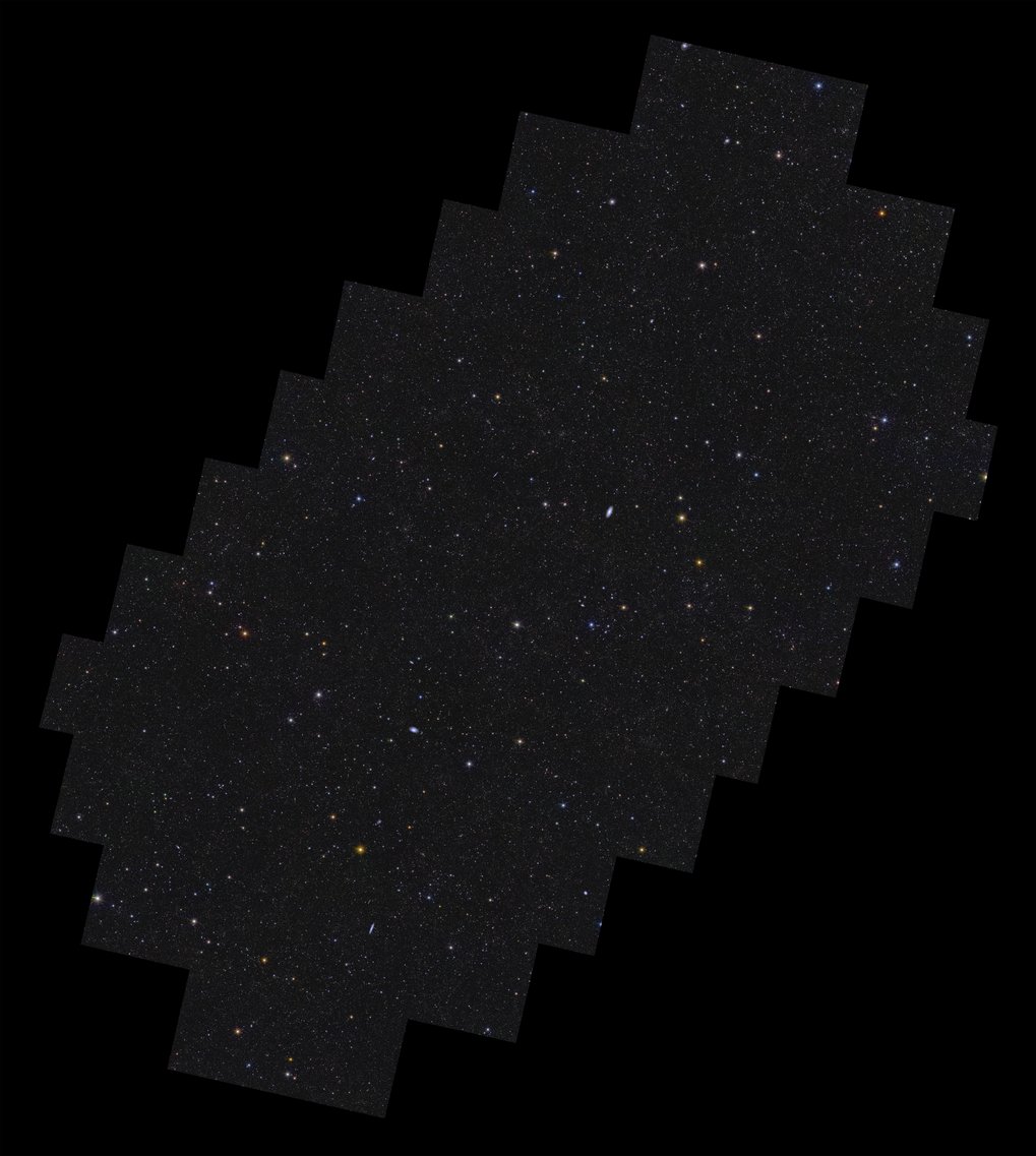 This is Euclid’s Deep Field South. After only one observation, the space telescope already spotted more than 11 million galaxies in this field. In the coming years, Euclid will make more observations of this field to reach its full depth. When looking at the image, a glimpse of the large-scale structure of the Universe can be seen. This is the organisation of galaxies along the so-called ‘cosmic web’. This web consists of huge clusters of galaxies connected to one another by strands of gas and invisible dark matter.Euclid’s Deep Field South covers 28.1 square degrees in the southern constellation of Horologium, the pendulum clock. This field has not been covered to date by any deep sky survey and so has a huge potential for new, exciting discoveries. On a black background lies a rectangular shape with stepped edges all around, oriented with its long axis pointing from bottom left to top right. Contained within the shape are more than 11 million galaxies, and stars of various size, brightness and colour. Some galaxies are easily identifiable by their fuzzy elongated shapes. There is a hint of more densely populated regions of galaxies being organised into a web-like structure of filaments that permeates the image.
