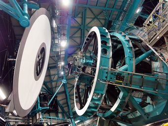 Kalibration des Simonyi-Teleskops des Vera C. Rubin Observatoriums. Hier misst die Kamera mit ihren 3,2 Milliarden Pixeln das homogene Licht, das der weiße ringförmige Bildschirm links aussendet. Abweichungen des aufgenommenen Bildes von einem homogenen Bild gehen zurück auf natürliche Schwankungen, die sich durch die Herstellung der Kamera ergeben. Die Kalibration dient dazu, diese Eigenheiten der Detektoren zu erfassen, welche dann bei künftigen astronomischen Beobachtungen berücksichtigt werden. Große mechanische Struktur eines Teleskops