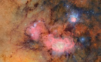 Diese Aufnahme der bekannten Sternentstehungsgebiete Messier 8 und Messier 20 hat fast 5 Gigapixel und besteht aus 678 Einzelaufnahmen, die über einen Zeitraum von 7,2 Stunden aufgenommen wurden. Kein anderes Observatorium kann einen so großen Bereich des Himmels in so kurzer Zeit bei dieser Tiefe ablichten. Der Trifidnebel Messier 20 ist ein farbenfroher Gasnebel in 5000 Lichtjahren Entfernung im Sternbild Schütze. Dunkle Staubbahnen teilen das von blauem Leuchten umgebene rosa Leuchten von Wasserstoffgas in drei Teile – daher der Name. Unterhalb des Trifidnebels befindet sich der Lagunennebel Messier 8, der sich mit 4000 Lichtjahren in etwas geringerer Entfernung befindet. Dichtes Milchstraßen-Sternenfeld, davor ein größerer rosa Bereich (Lagunennebel) und oben rechts ein bläulich umrandeter, dreigeteilter rosa Bereich (Trifidnebel)