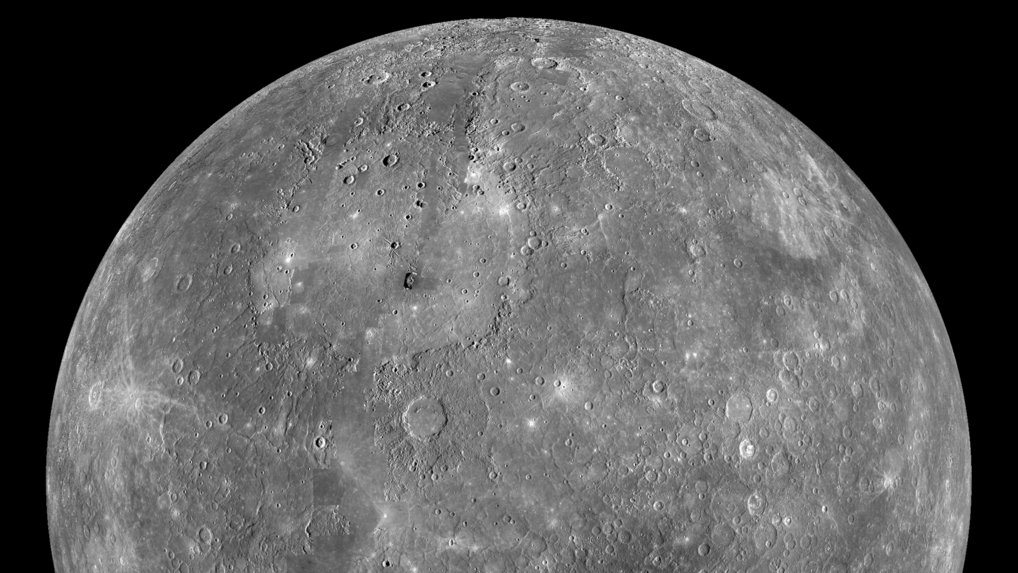 Ein teilweises Schwarz-Weiß-Mosaik des Planeten Merkur vor schwarzem Hintergrund, aufgenommen von der Raumsonde MESSENGER. Die graue, sphärische Oberfläche ist stark verkratert und von Einschlagstellen unterschiedlicher Größe gezeichnet, was auf Milliarden Jahre kosmischen Bombardements hindeutet. Das Oberflächenmaterial ist dunkel und basaltisch, mit markanten hellen Strahlenkratern, in denen frisches Material aus dem Untergrund ausgeworfen wurde. Da keine Atmosphäre die Sicht trübt, zeigt das Bild scharfe, kontrastreiche Strukturen, die eine Welt beschreiben, die direkt der Weltraumumgebung und der Sonnenstrahlung ausgesetzt ist.