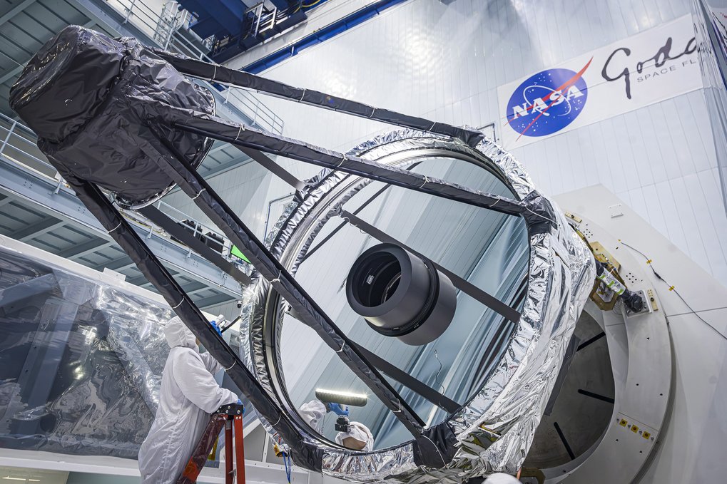 Großer Spiegelteleskop im Reinraum mit NASA-Logo im Hintergrund.